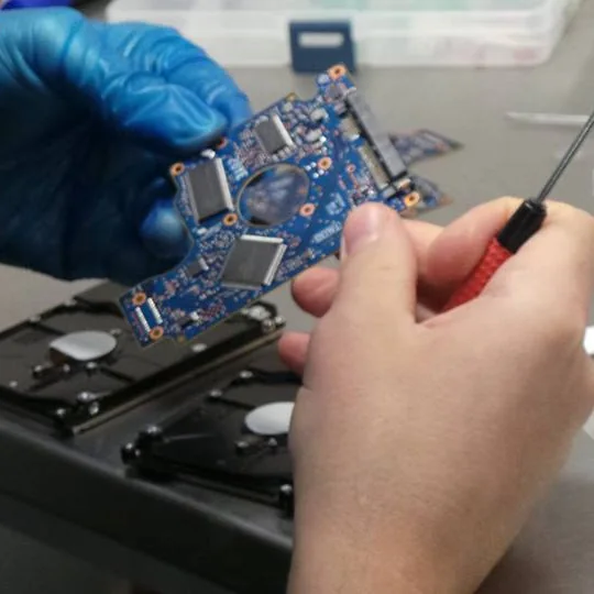 Technicien Mac France inspectant une carte électronique au tournevis de précision